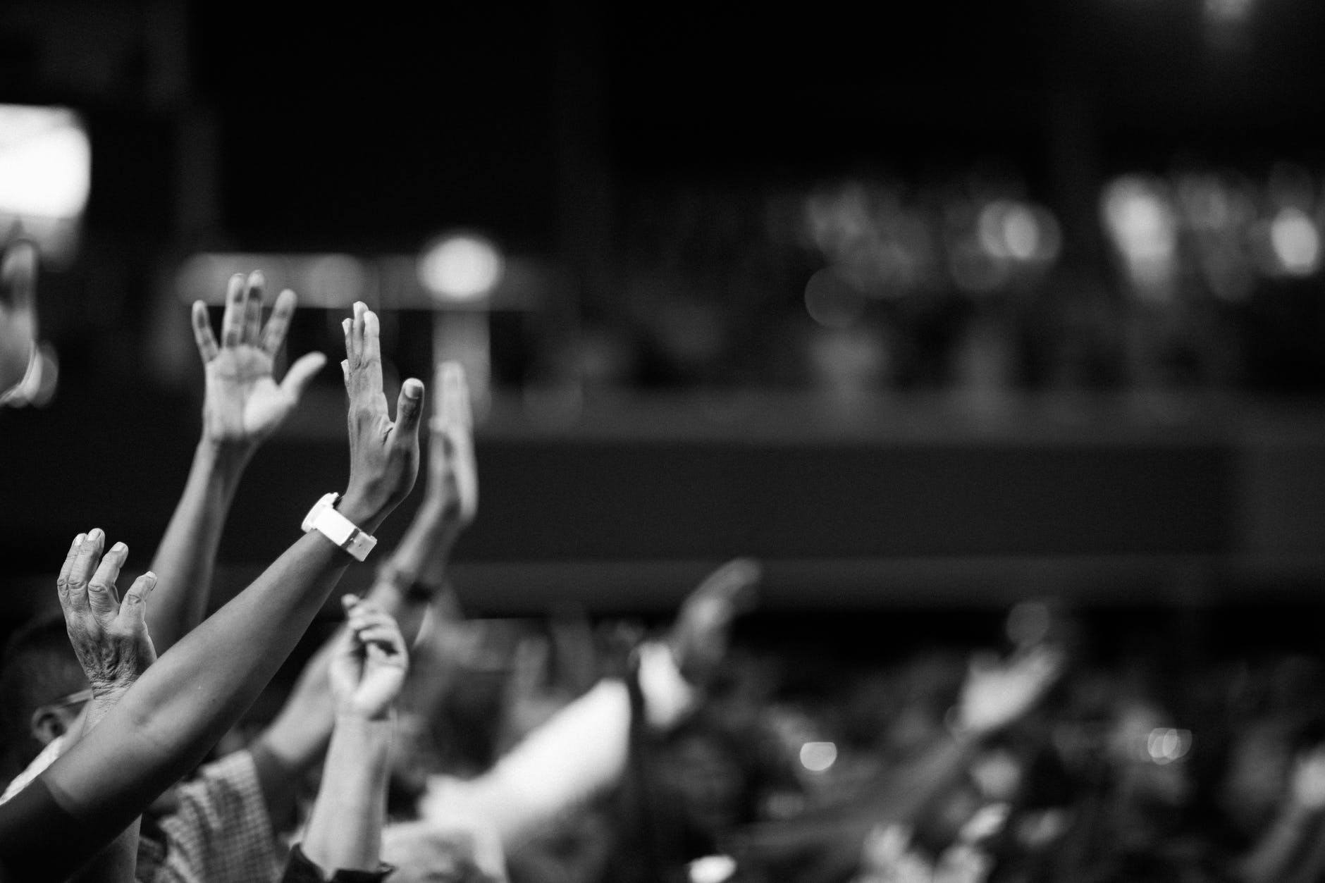 Black and white photo of a crowd with individuals raising their hands 